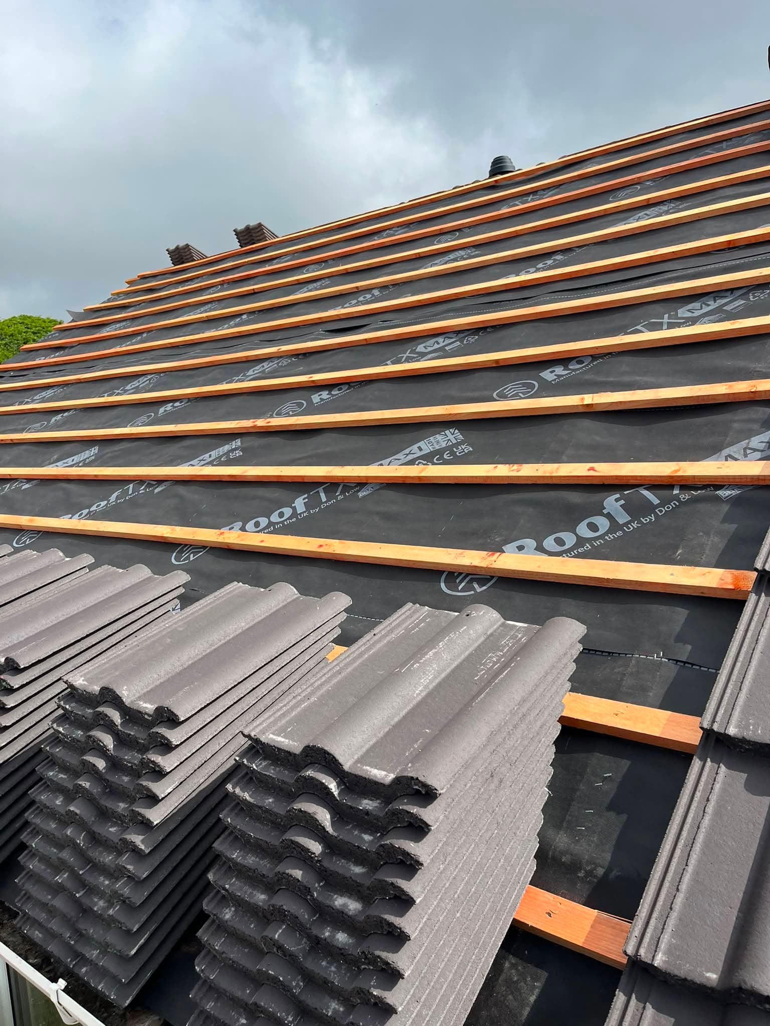 Battens and membrane laid with new concrete tiles stacked ready to be fitted