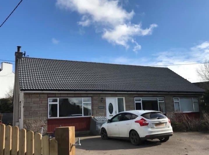 Bungalow with a completed new dark tile roof by RML Roofing Services